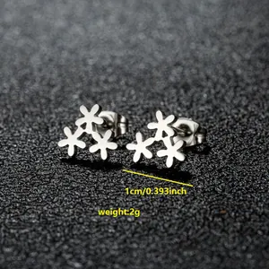 Detalle macro de pendientes de acero inoxidable con tres flores y especificaciones de peso