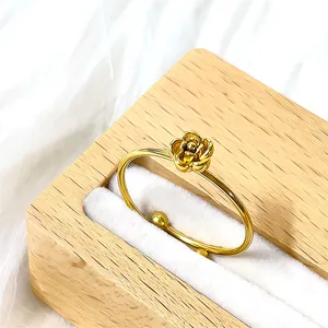 Détail d'un bracelet jonc rose doré aux pétales fins dans une boîte à bijoux en bois