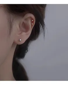 Vue rapprochée de boucles d'oreilles boules en acier argenté de tailles variées sur l'oreille