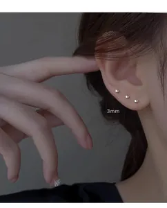 Trois boucles d'oreilles boules minimalistes de 3 mm sur le lobe et le cartilage