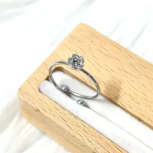 Gros plan d'une bague florale ajustable en argent avec une petite fleur sur support en bois