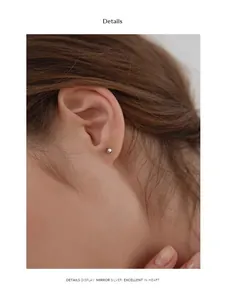 Gros plan détaillé d'une boucle d'oreille boule en acier argenté miroir sur l'oreille