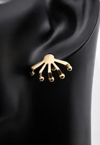 Primer plano de pendiente dorado con diseño de garra y cuentas en maniquí negro
