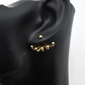 Vista detallada del pendiente de acero inoxidable dorado en un modelo de oreja
