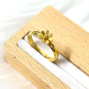 Macro d'une bague marguerite dorée sur un support de bijoux blanc avec détails en bois