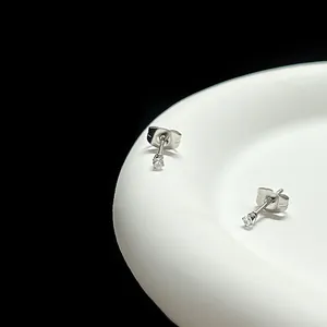 Vue macro de boucles d'oreilles minimalistes argentées serties de zircons à quatre griffes