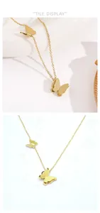 Detalle de collar de doble mariposa dorada con acabado mate y cadena de eslabones cruzados