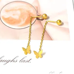 Detail of gold butterfly tassel earrings with spherical studs on an artistic background