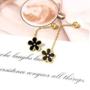 Detail of long floral tassel earrings with black and gold enamel on a white card