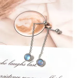 Close-up of minimalist silver tassel earrings with blue gemstone on magazine background