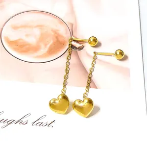 Detailed view of long gold chain earrings with polished heart pendants on decor card