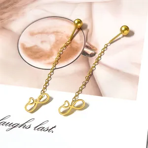 Detailed close-up of golden infinity heart tassel earrings resting on a magazine page