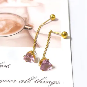 Detail of gold chain earrings featuring pink heart zircon pendants and delicate fringe