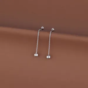 Detailed view of silver flower tassel drop earrings on a minimalist brown background