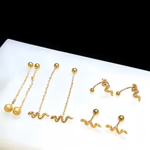 Detail of four golden snake earrings featuring ball chains and U-shaped studs on white stand