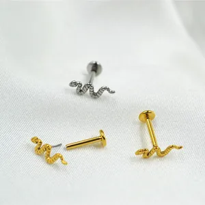 Macro-detail van slangvormige labret piercings in goud en zilver met schubtextuur