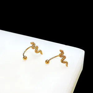 Detailed view of golden snake-shaped stud earrings with textured scales on a white block