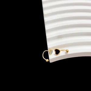 Gedetailleerde macro van goudkleurige U-vormige oorbellen met zwart emaille hart