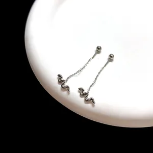 Minimalist stainless steel snake drop earrings with chain and ball stud on white ceramic