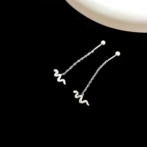 Detailed view of silver snake drop earrings with fine chains on black velvet background
