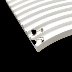 Detail van goudkleurige U-vormige schroefoorbellen met zwarte hartvormige hangers