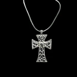 Macro detail of gothic silver cross pendant with black rhinestones and beaded edges