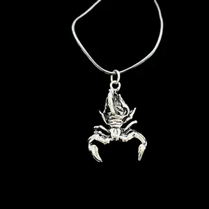 Detailed view of a silver scorpion pendant necklace with intricate carvings on black background