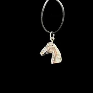 Detailed close-up of a carved silver horse head pendant with black necklace cord