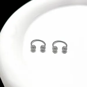 Macro view of silver C-shaped cartilage studs with polished bar and matte texture beads