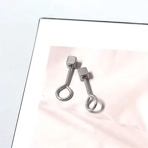 Macro detail van geometrische titanium stalen oorknopjes met gepolijste kubus en lusontwerp