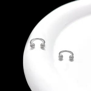 Macro shot of silver-tone C-shape stud earrings with shimmering frosted texture finish