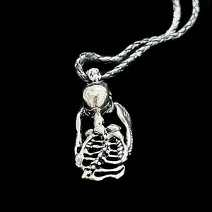 Detailed view of a silver-toned gothic skeleton pendant with matching chain on black