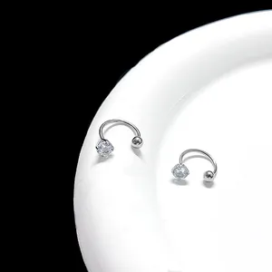 Macro shot of silver horseshoe U-shaped piercing with round cubic zirconia and metal bead