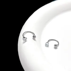 Close-up of silver horseshoe piercing with clear cubic zirconia and polished metal ball