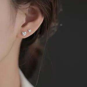 Détail de boucles d'oreilles cœur en acier titane avec zircon sur l'oreille de femme