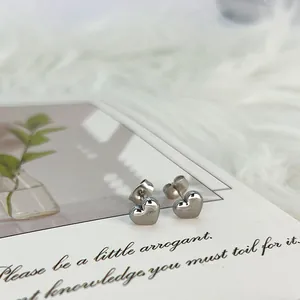 Primer plano de pendientes de corazón en plata pulida sobre un fondo de tarjeta elegante