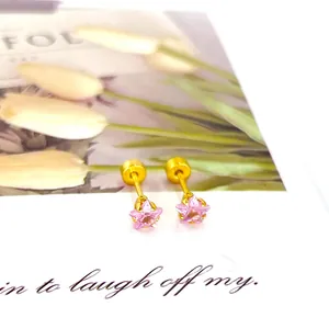 Vue détaillée des boucles d'oreilles étoile rose et dorée sur carte décorative