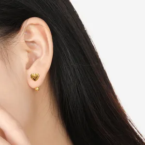 Pendientes de corazón dorado minimalistas en modelo con diseño pulido y geométrico