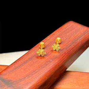 Makroaufnahme goldener Schneeflocken-Ohrstecker mit Schraubverschluss auf Holzständer