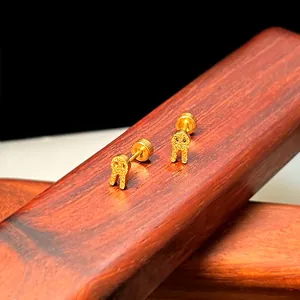 Detailaufnahme goldener mattierter Schleifen-Ohrstecker auf Holzstruktur