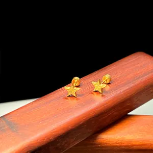 Detailansicht goldener mattierter Stern-Ohrstecker mit Kugelverschluss auf dunklem Holz
