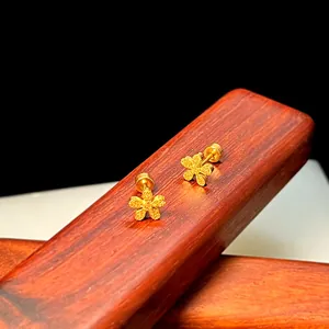 Makroaufnahme matter goldener Blumen-Ohrstecker mit Schraubverschluss auf Holz