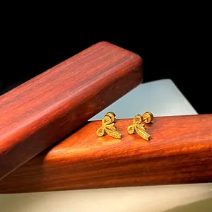Makroaufnahme goldener Schleifen-Ohrstecker aus Titanstahl mit mattierter Oberfläche