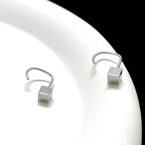 Nahaufnahme minimalistischer quadratischer Ohrstecker aus poliertem Silber auf weißem Tablett