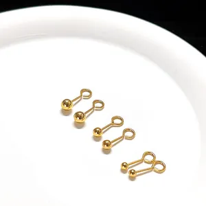 Close-up van drie paar gouden titanium stalen bolletjes oorbellen op wit bord