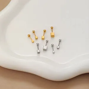 Makroaufnahme quadratischer Minimalist-Ohrstecker in Gold und Silber auf einem Tablett