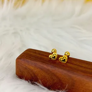 Détail de boucles d'oreilles cœur dorées avec émail noir et fermoirs à vis sécurisés