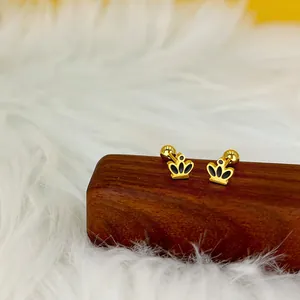 Détail de boucles d'oreilles couronne dorées avec émail noir sur support en bois
