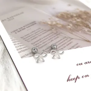 Macro detail of silver bow stud earrings with secure ball back on a display card