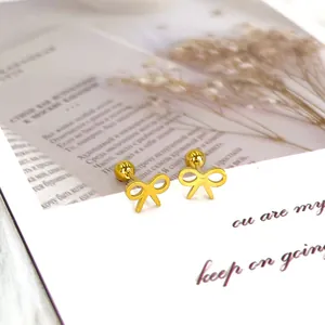 Close-up of golden bow-knot earrings with secure screw-back closure on a gift card